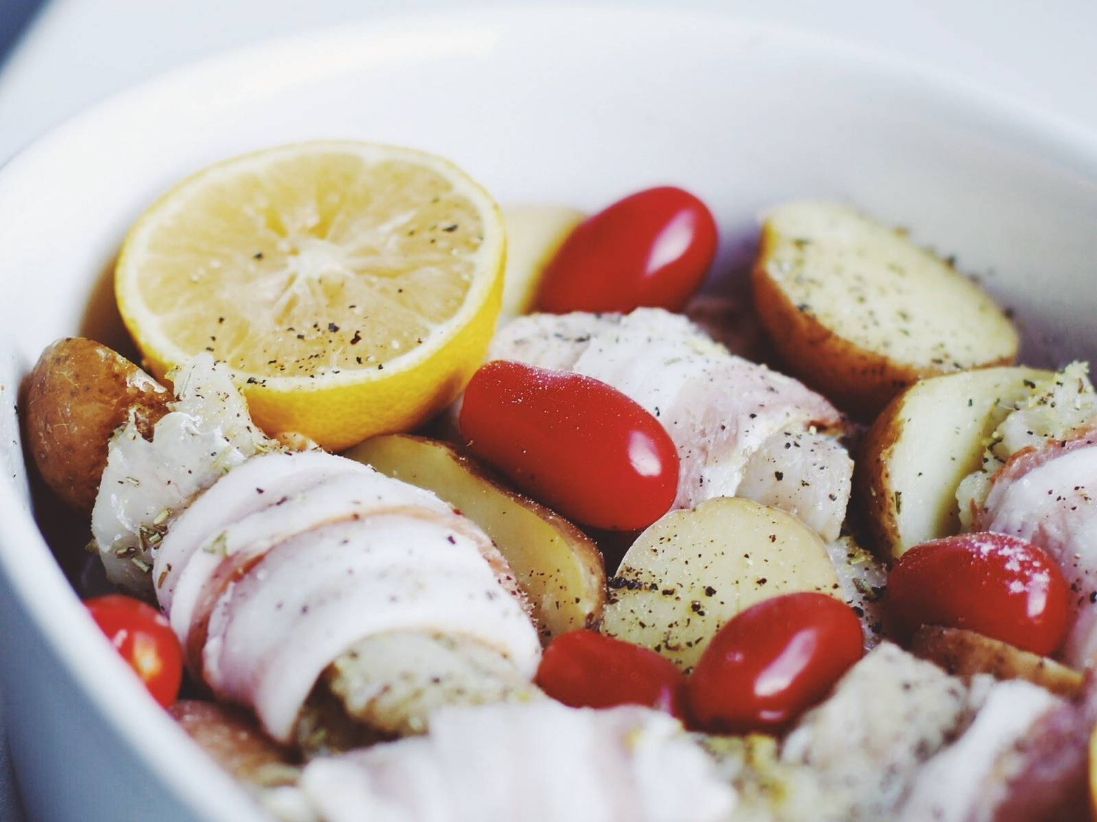 Cod baked in the oven with potatoes, tomatoes and bacon